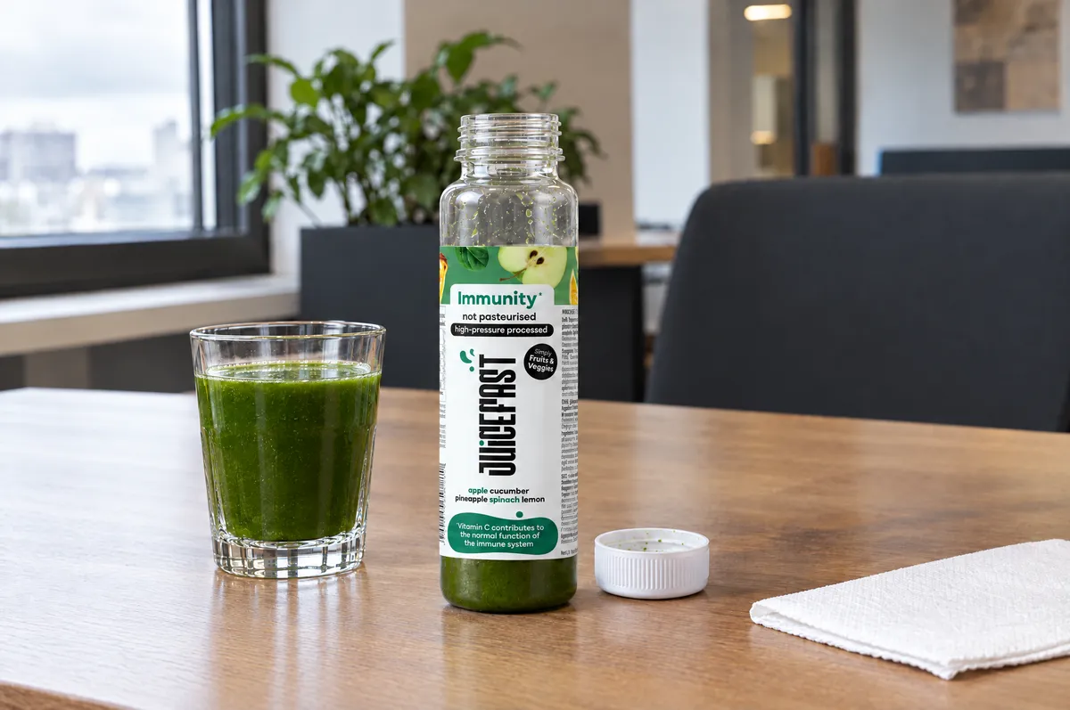 Immunity sok u čaši uz otvorenu, djelomično ispražnjenu bočicu od 250 ml